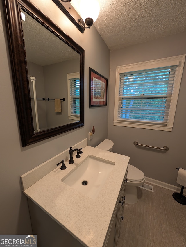 bathroom with a textured ceiling, vanity, toilet, and hardwood / wood-style floors