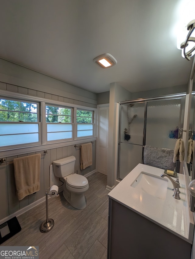 bathroom featuring vanity, toilet, wood-type flooring, and walk in shower