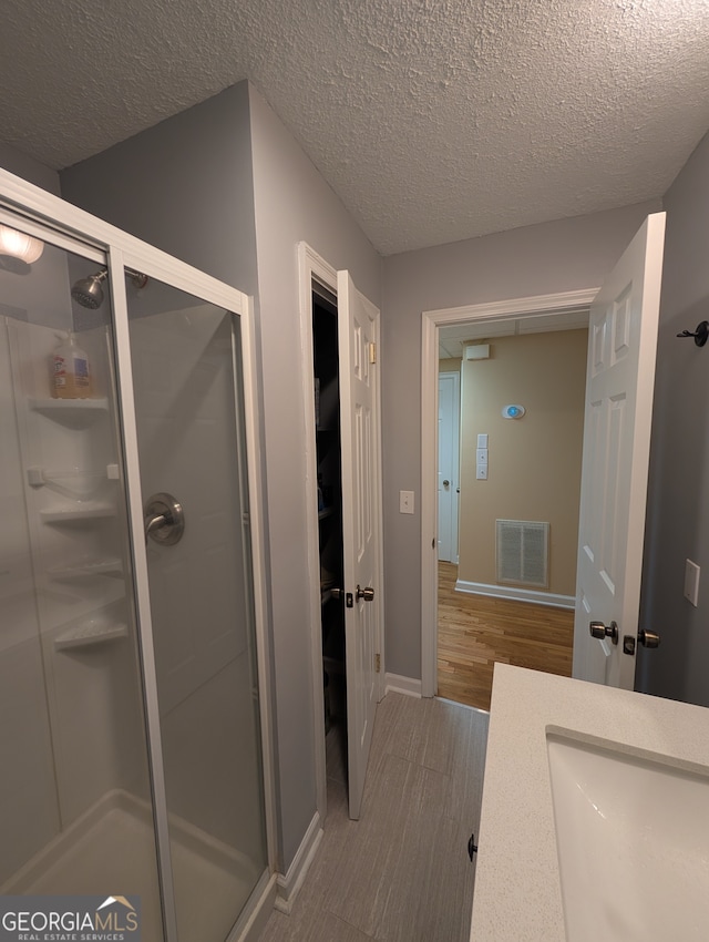 bathroom featuring a textured ceiling, vanity, hardwood / wood-style floors, and an enclosed shower