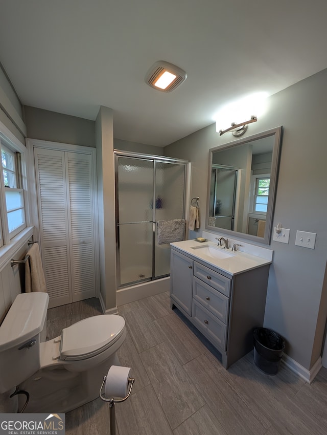 bathroom with vanity, toilet, a wealth of natural light, and an enclosed shower