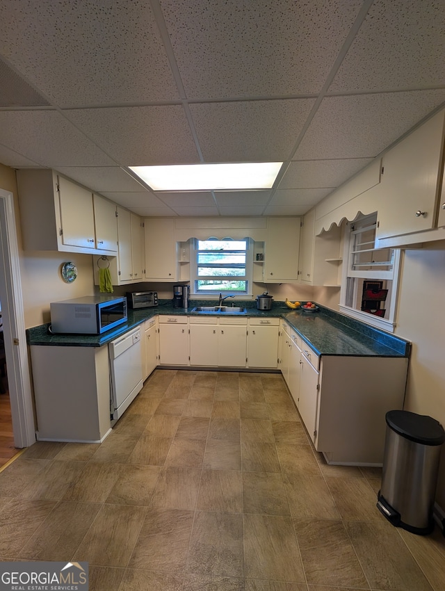 kitchen with white cabinetry, a paneled ceiling, white dishwasher, and sink