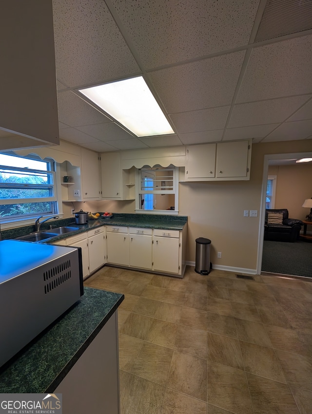 kitchen featuring a drop ceiling, white cabinetry, and sink