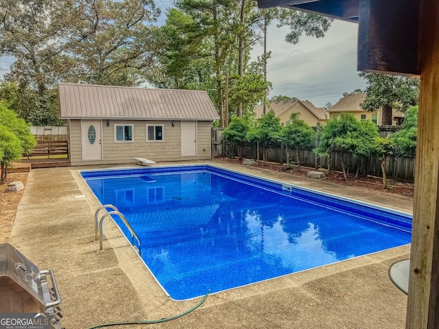 view of swimming pool with a diving board and an outbuilding