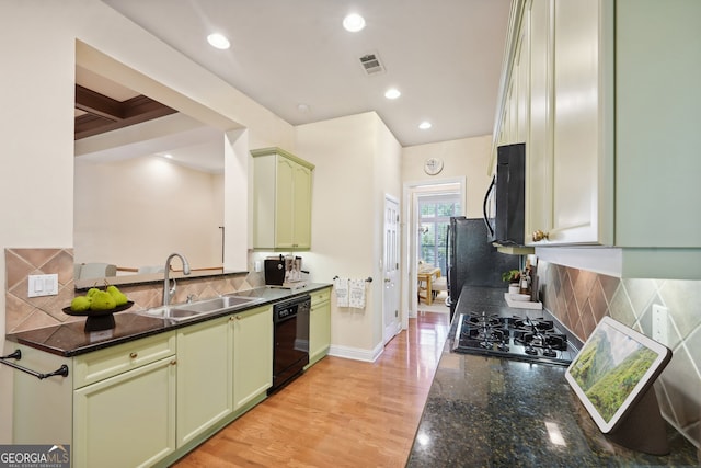 kitchen featuring backsplash, light wood-type flooring, sink, black appliances, and dark stone counters