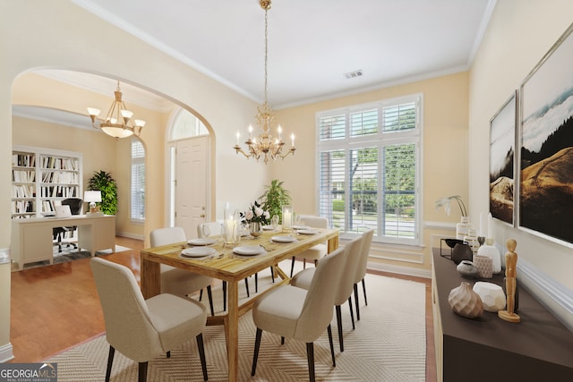 dining area with wood-type flooring, crown molding, and a notable chandelier