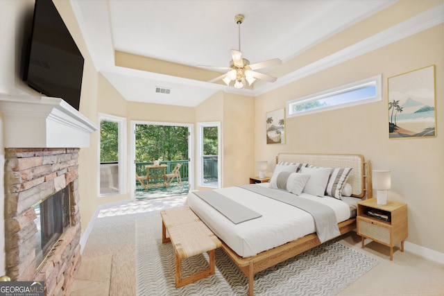 carpeted bedroom featuring ceiling fan, a stone fireplace, multiple windows, and access to outside