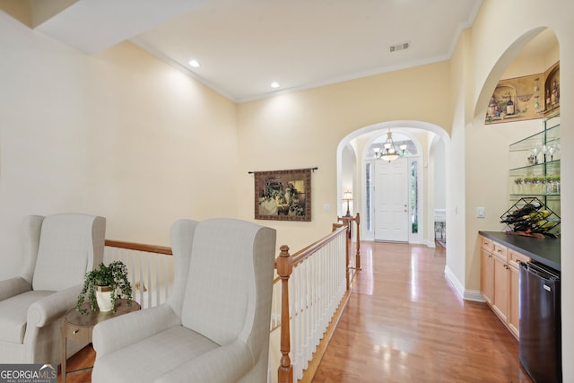 corridor featuring ornamental molding, a chandelier, and light hardwood / wood-style flooring