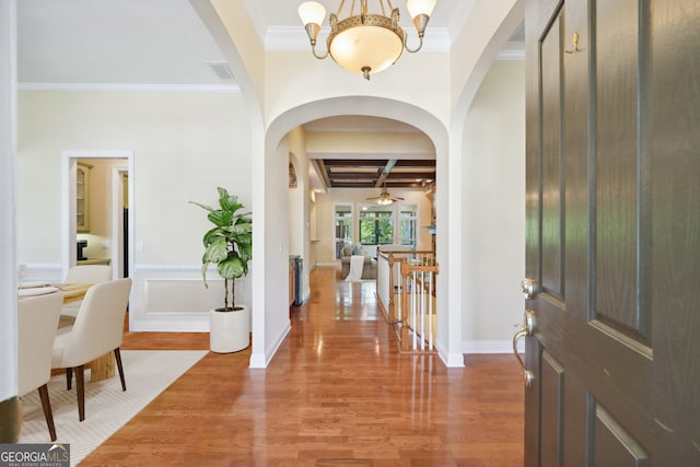 foyer with crown molding, an inviting chandelier, beamed ceiling, and wood-type flooring