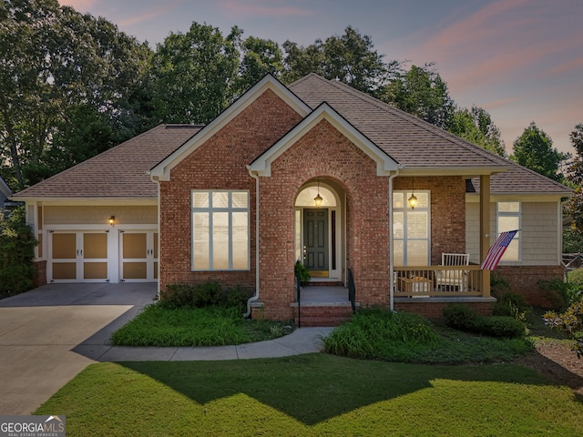 view of front of home with a porch, a garage, and a lawn