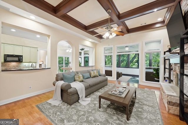 living room with coffered ceiling, ceiling fan, light hardwood / wood-style floors, and beam ceiling