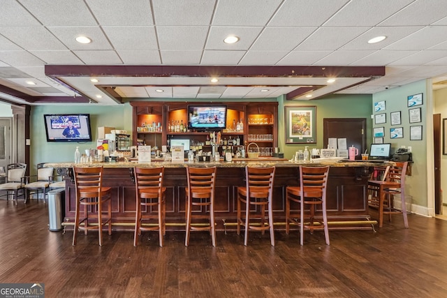 bar featuring light stone counters, dark hardwood / wood-style flooring, and a drop ceiling