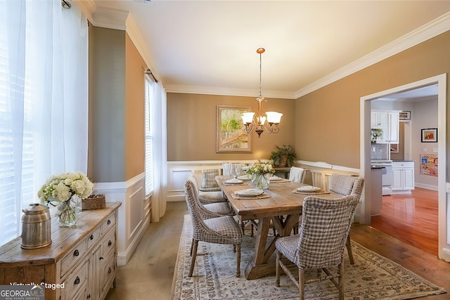 dining area featuring ornamental molding, wainscoting, and light wood finished floors