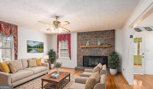 living area featuring a brick fireplace, ornamental molding, a wealth of natural light, and wood finished floors