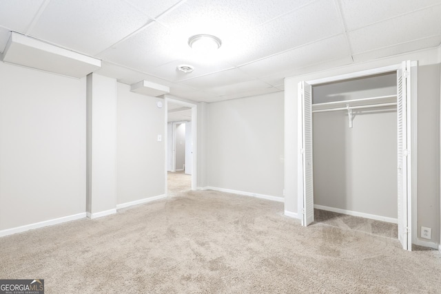 unfurnished bedroom with a paneled ceiling, baseboards, carpet, and a closet