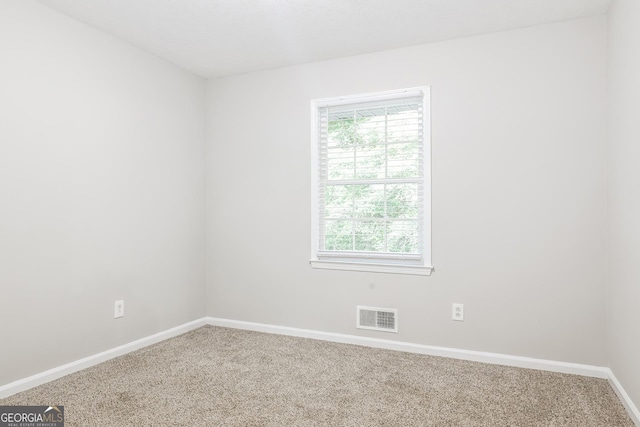 carpeted spare room with visible vents and baseboards