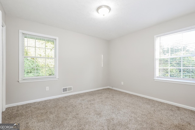 carpeted spare room featuring visible vents and baseboards