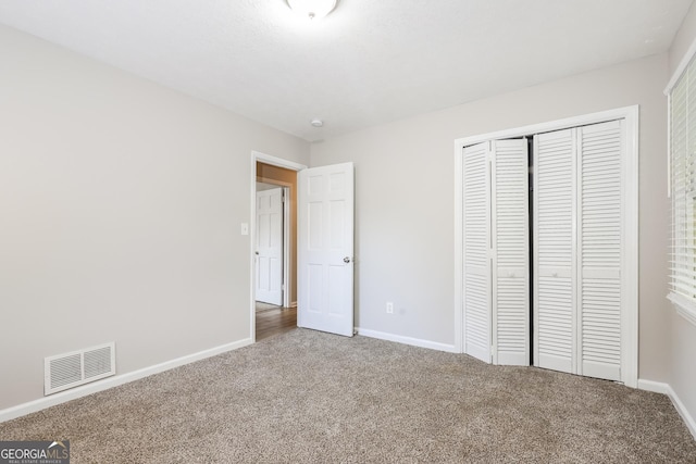 unfurnished bedroom with visible vents, baseboards, a closet, and carpet flooring