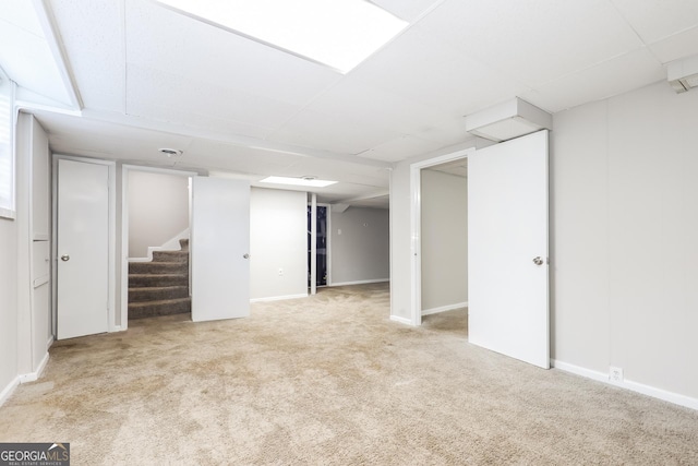 finished basement with a drop ceiling, stairs, baseboards, and carpet floors