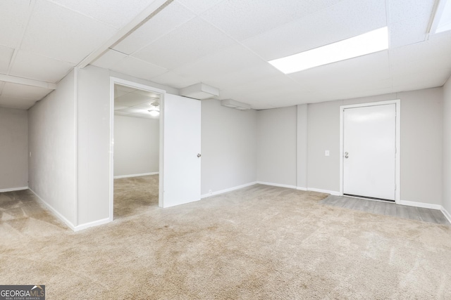 finished basement with carpet flooring, a paneled ceiling, and baseboards