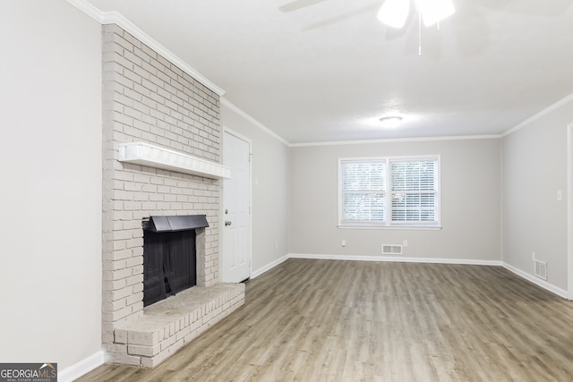 unfurnished living room featuring ornamental molding, ceiling fan, light wood-type flooring, and a brick fireplace