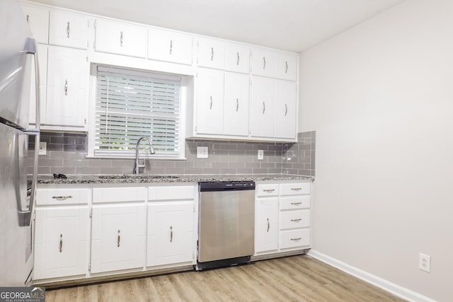 kitchen with light wood finished floors, backsplash, light stone counters, stainless steel appliances, and a sink