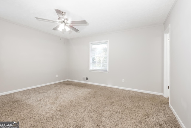 carpeted spare room featuring visible vents, a ceiling fan, baseboards, and ornamental molding