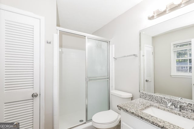 bathroom with vanity, a shower stall, toilet, and a closet