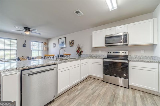 kitchen with stainless steel appliances, kitchen peninsula, sink, ceiling fan, and white cabinets