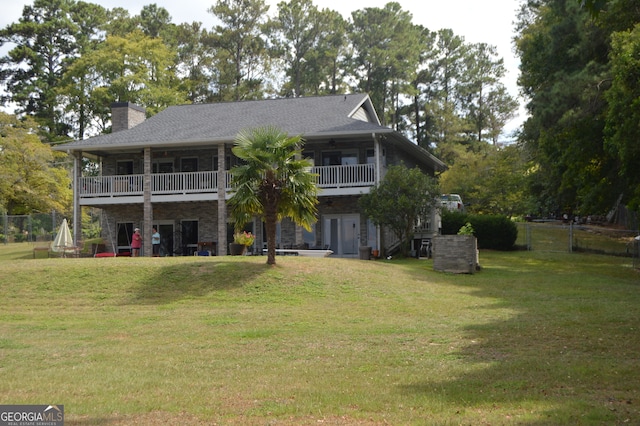 back of property featuring a balcony and a yard