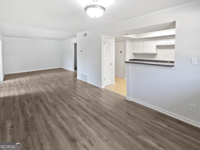 unfurnished living room featuring visible vents, baseboards, and wood finished floors