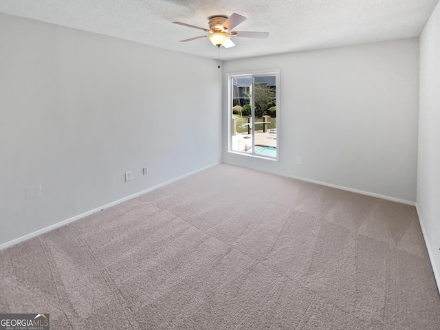 empty room featuring a textured ceiling, carpet flooring, baseboards, and ceiling fan