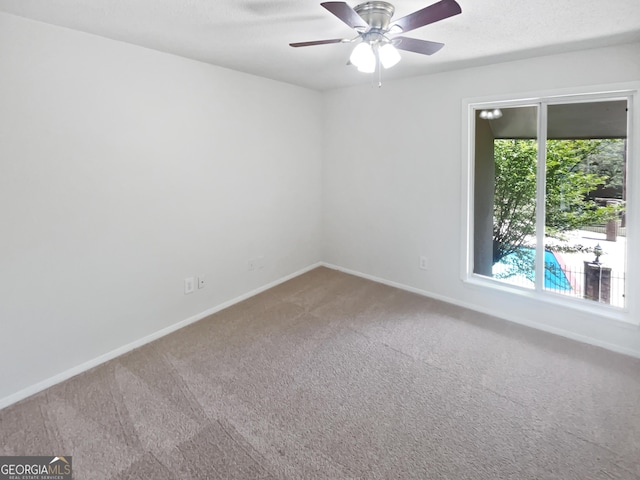 carpeted empty room with a ceiling fan and baseboards
