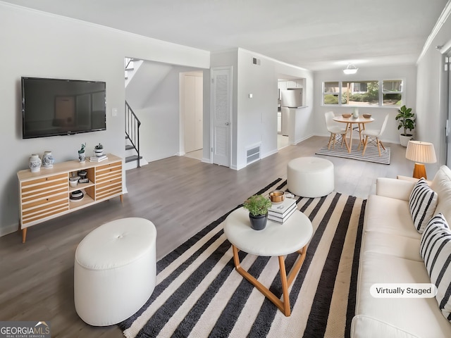 living room featuring wood finished floors, visible vents, and stairway