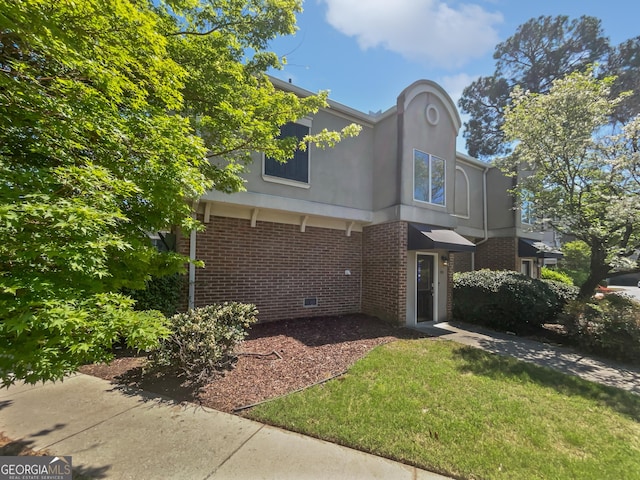 exterior space featuring crawl space, a lawn, brick siding, and stucco siding