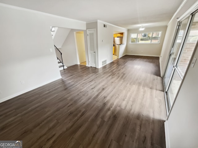 unfurnished living room featuring ornamental molding and dark wood-type flooring