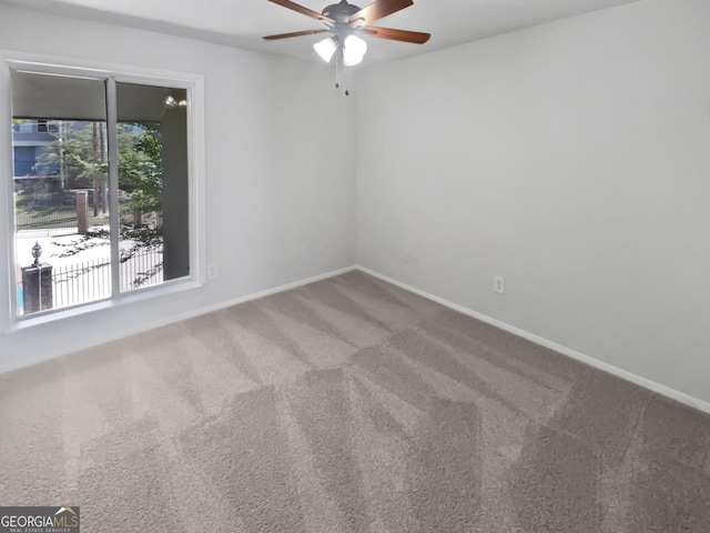 carpeted empty room featuring a ceiling fan and baseboards