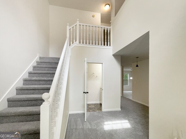 stairs with carpet flooring and a towering ceiling