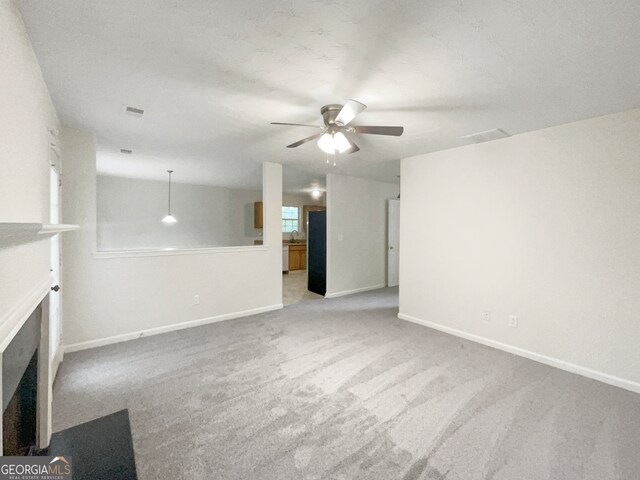 unfurnished living room featuring ceiling fan and light carpet