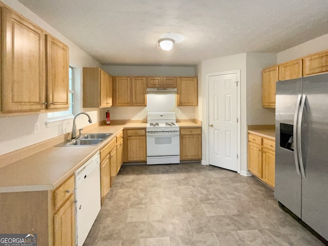 kitchen with white appliances, light brown cabinetry, sink, and a textured ceiling