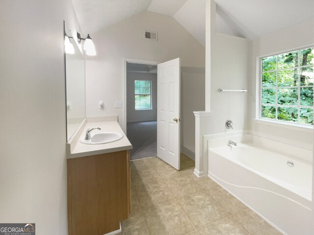 bathroom featuring vanity, lofted ceiling, a tub, and tile patterned flooring