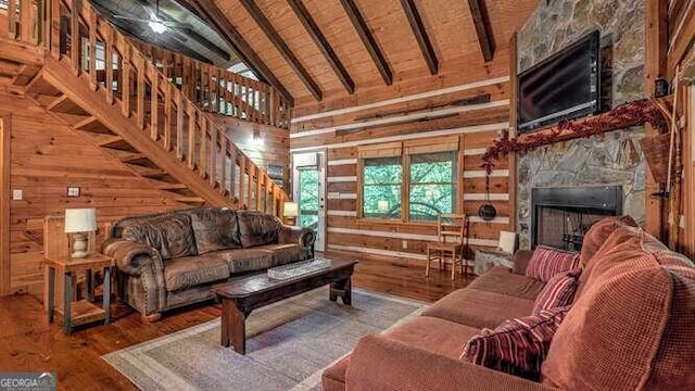 living room with a fireplace, beamed ceiling, wood walls, wood-type flooring, and wood ceiling