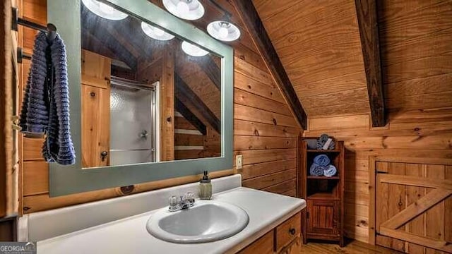 bathroom with vaulted ceiling, a shower with shower door, wood walls, and vanity