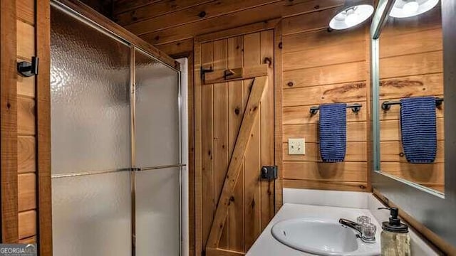 bathroom featuring wood walls, walk in shower, and sink