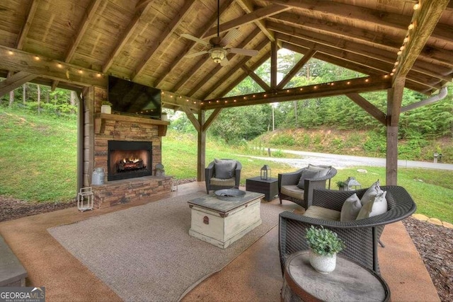 view of patio with an outdoor living space with a fireplace, ceiling fan, and a gazebo