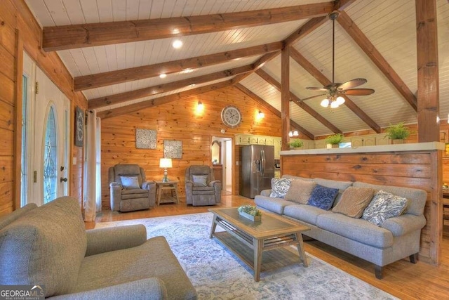 living room with ceiling fan, lofted ceiling with beams, wooden walls, and light hardwood / wood-style floors