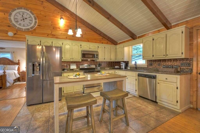 kitchen featuring light wood-type flooring, stainless steel appliances, a chandelier, beamed ceiling, and pendant lighting