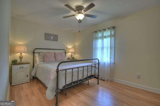 bedroom with a textured ceiling, light hardwood / wood-style flooring, and ceiling fan