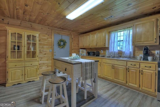 kitchen featuring wood walls, wood ceiling, light brown cabinetry, and light hardwood / wood-style flooring