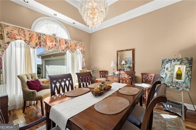 dining area with a wealth of natural light, crown molding, a notable chandelier, and hardwood / wood-style flooring