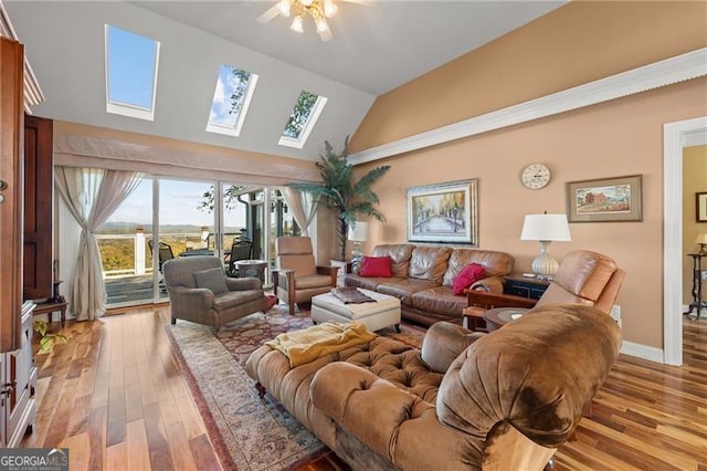 living room with a skylight, high vaulted ceiling, and light hardwood / wood-style flooring